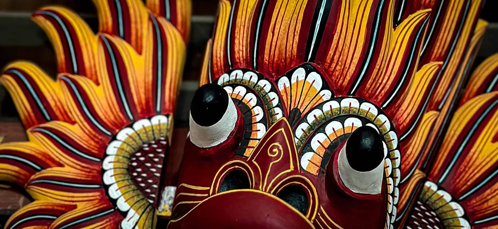 Close-up of a brightly painted traditional Sri Lankan wooden mask with bold colours and intricate carved details