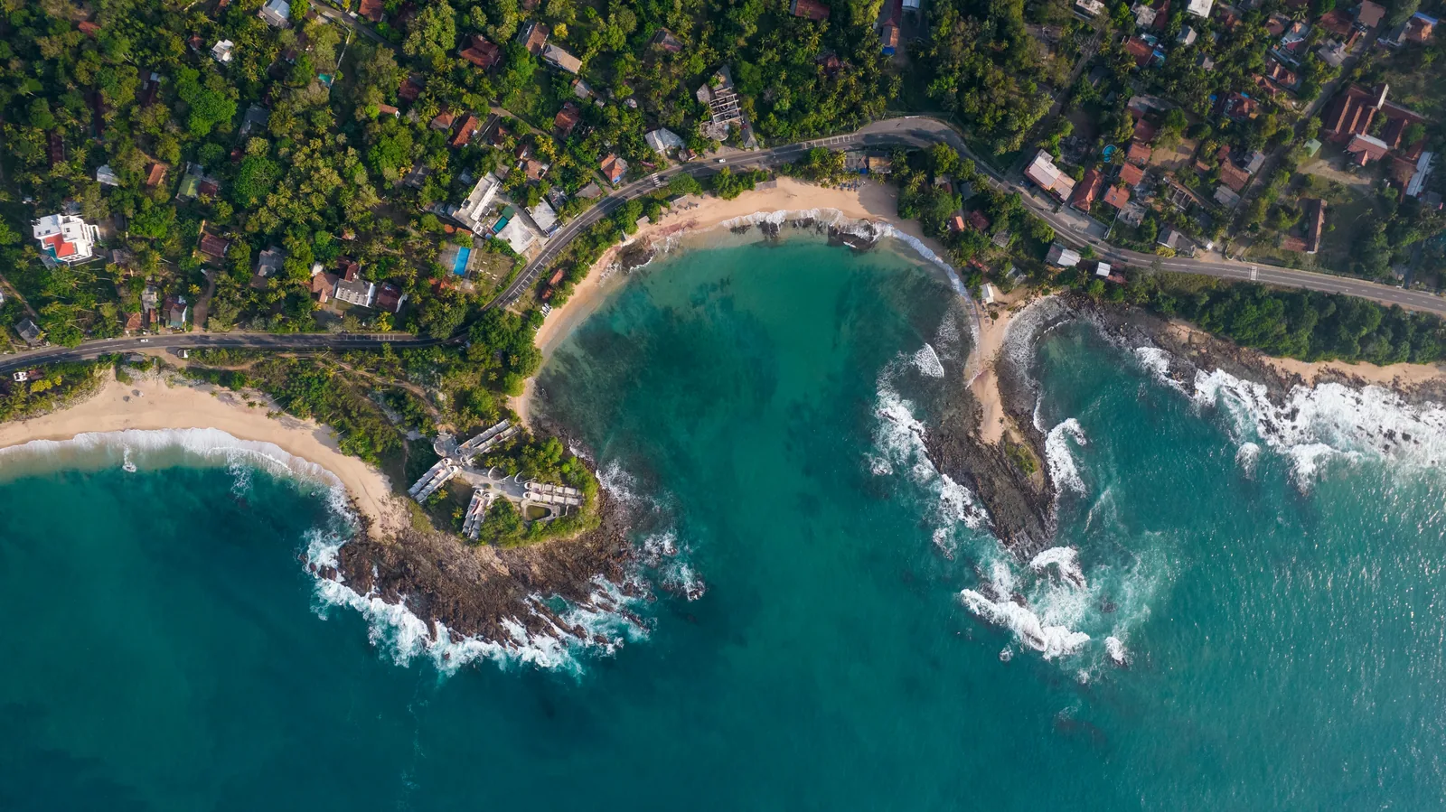 Aerial view of the Sri Lanka coastline with turquoise ocean, tropical palm trees, and white sandy beach showing the island's natural beauty