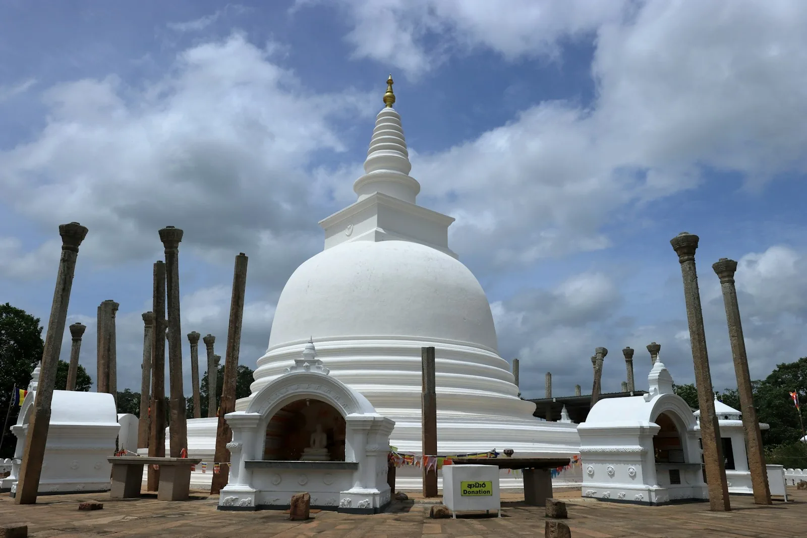 The ancient Ruwanwelisaya stupa at sunrise in Anuradhapura, Sri Lanka, reflected in still water with Buddhist pilgrims in white walking the perimeter
