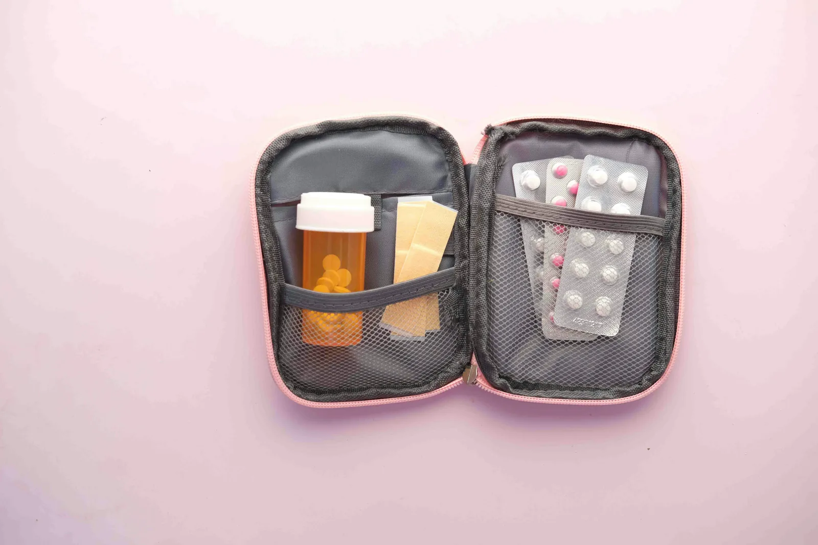 Open travel medicine kit with pill bottles, blister packs of tablets and band-aids - essential health supplies for a Sri Lanka trip