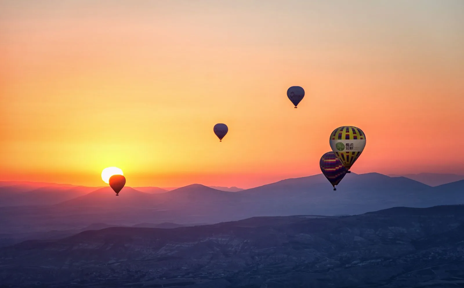 Hot air balloons silhouetted against a vivid orange and pink sunrise sky
