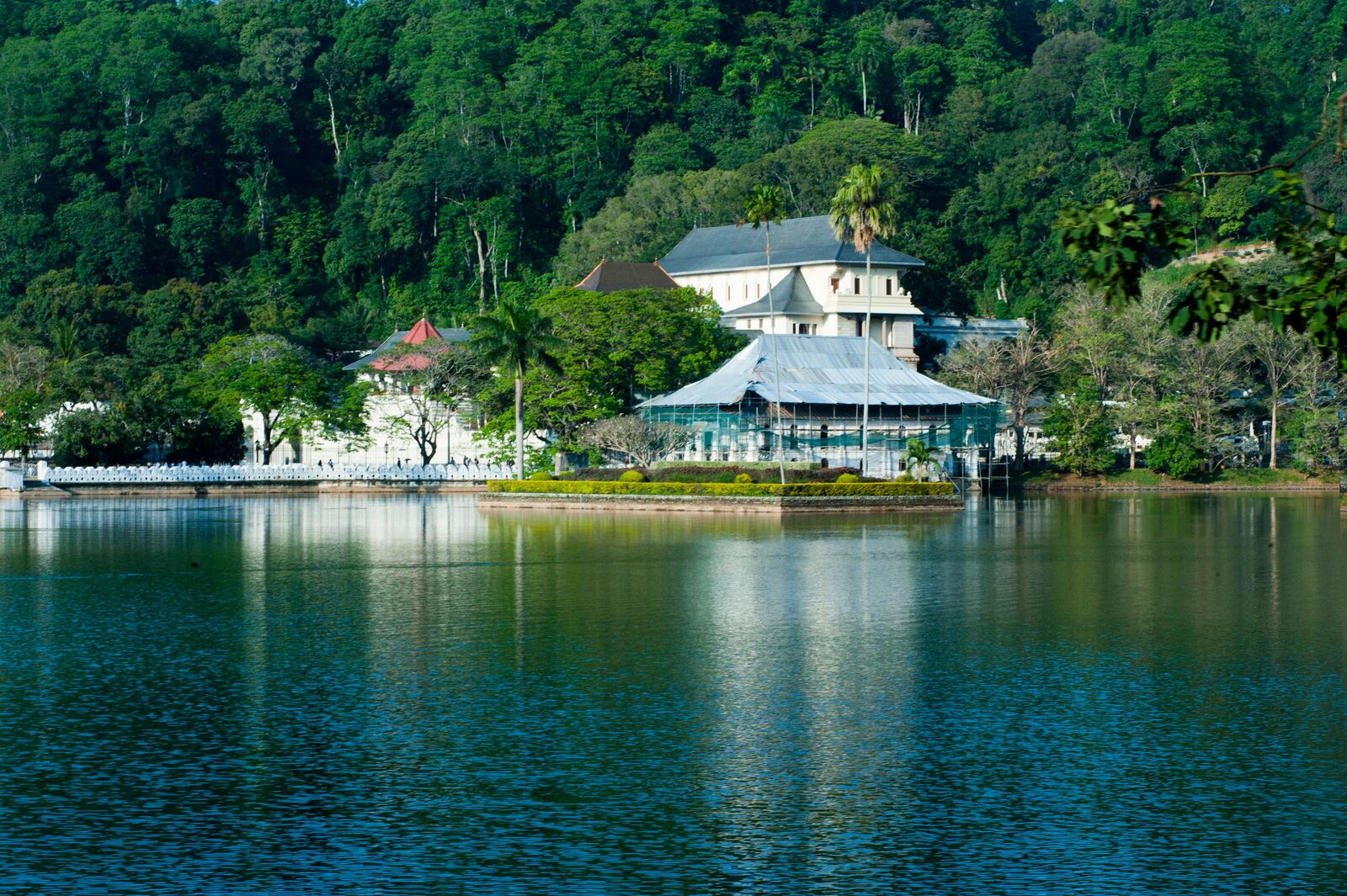 Kandy Lake at dusk with the Temple of the Tooth illuminated in the background, surrounded by forested hills