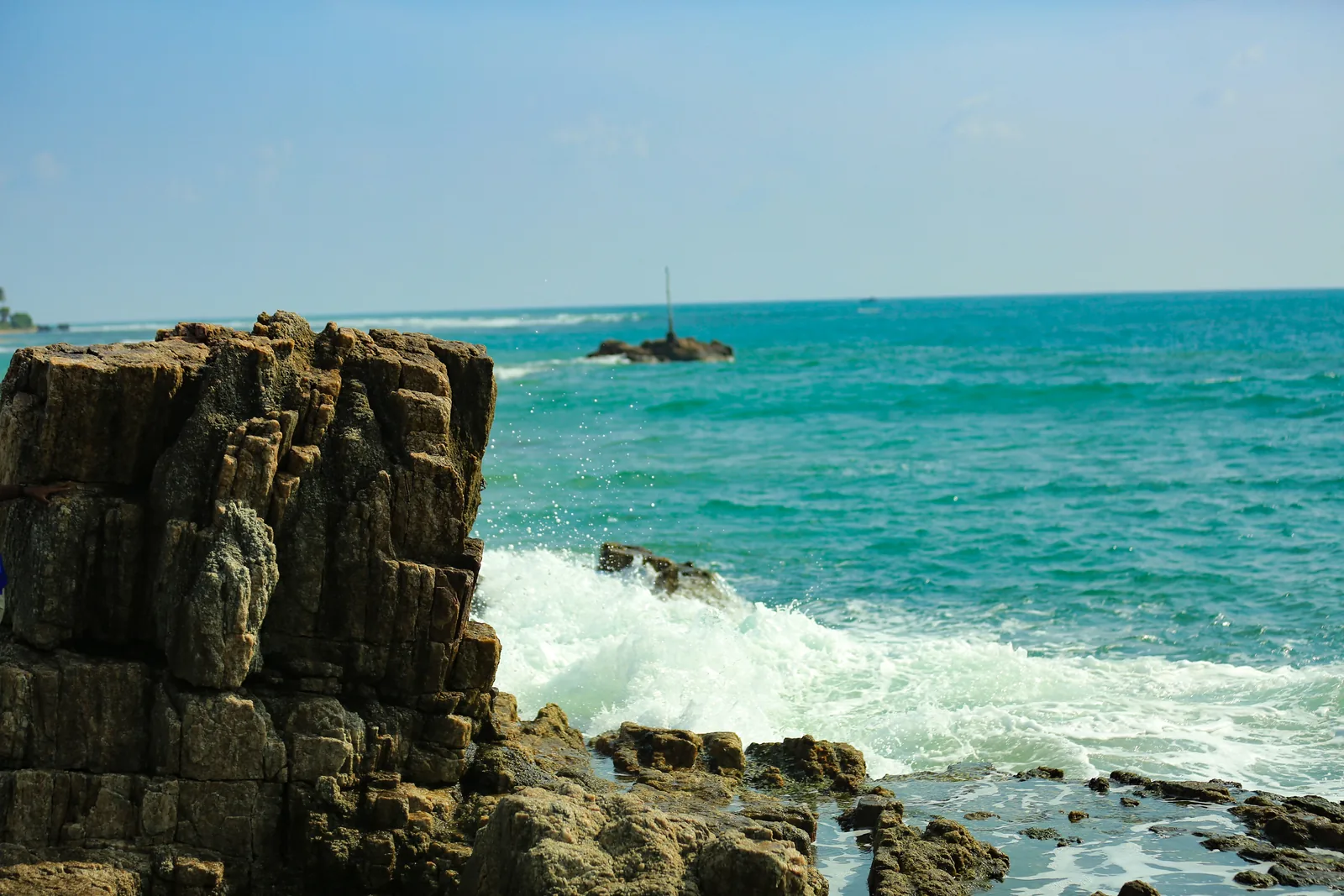 Rocky coastline with turquoise waves crashing against the rugged rocks of Trincomalee's east coast, Sri Lanka