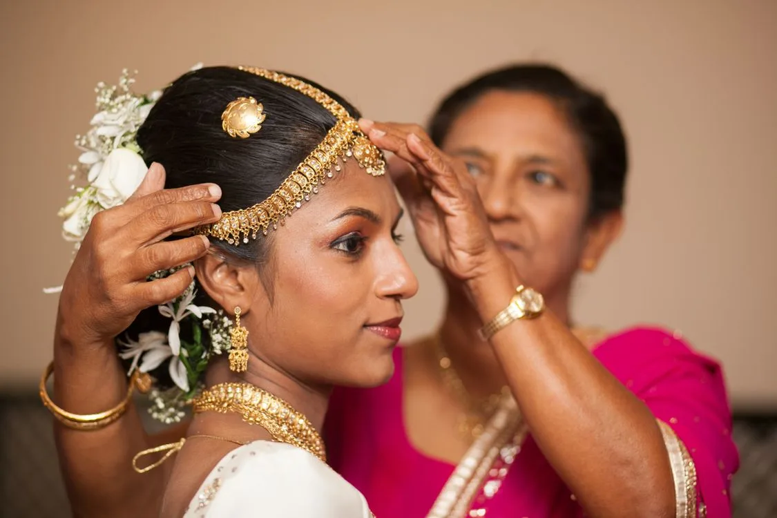 A Sri Lankan mother helping her daughter into traditional Kandyan bridal jewellery before the wedding ceremony - a ritual common to both Sri Lankan and Indian wedding traditions
