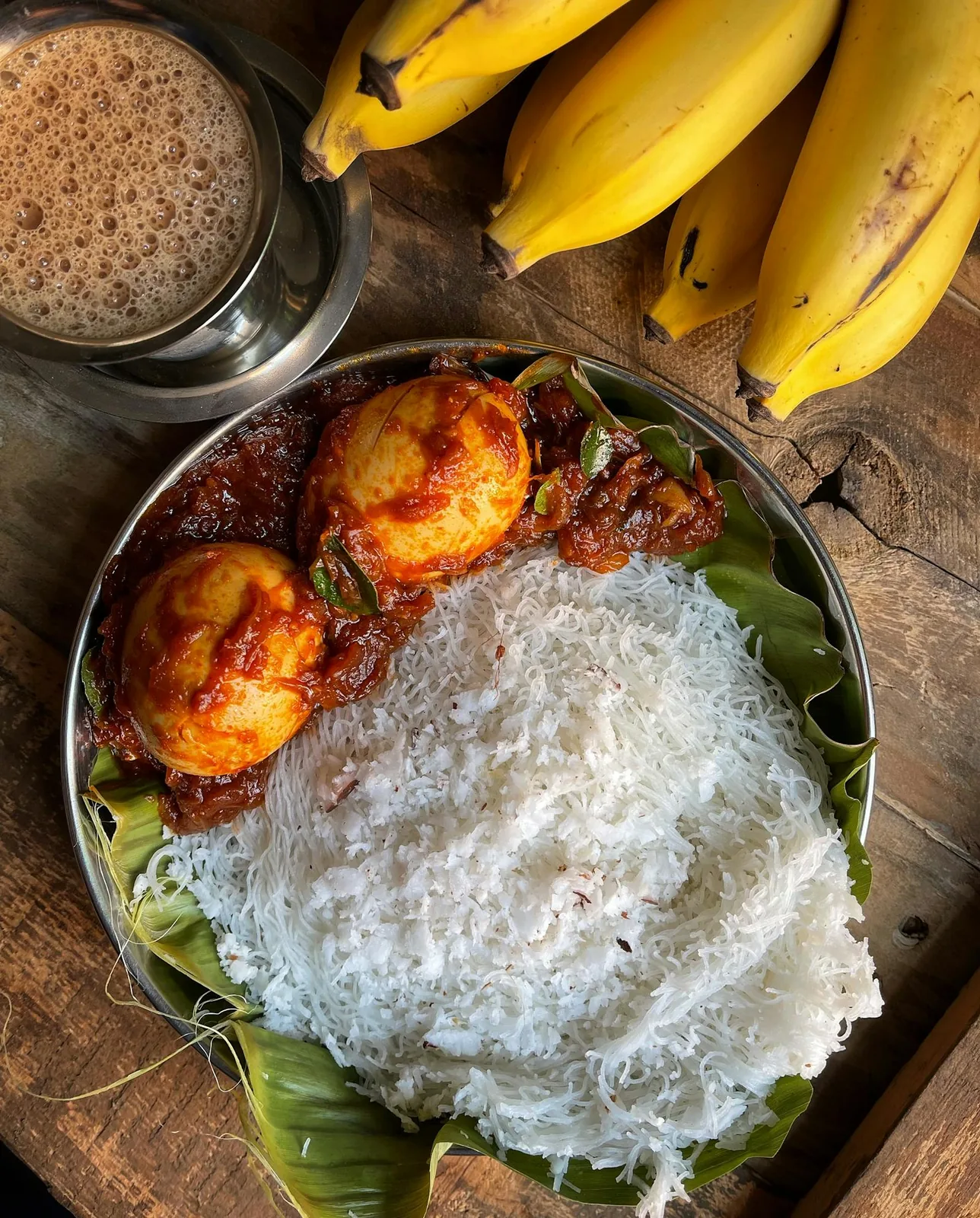 Sri Lankan string hoppers with egg curry, coconut sambol and tea served on a banana leaf