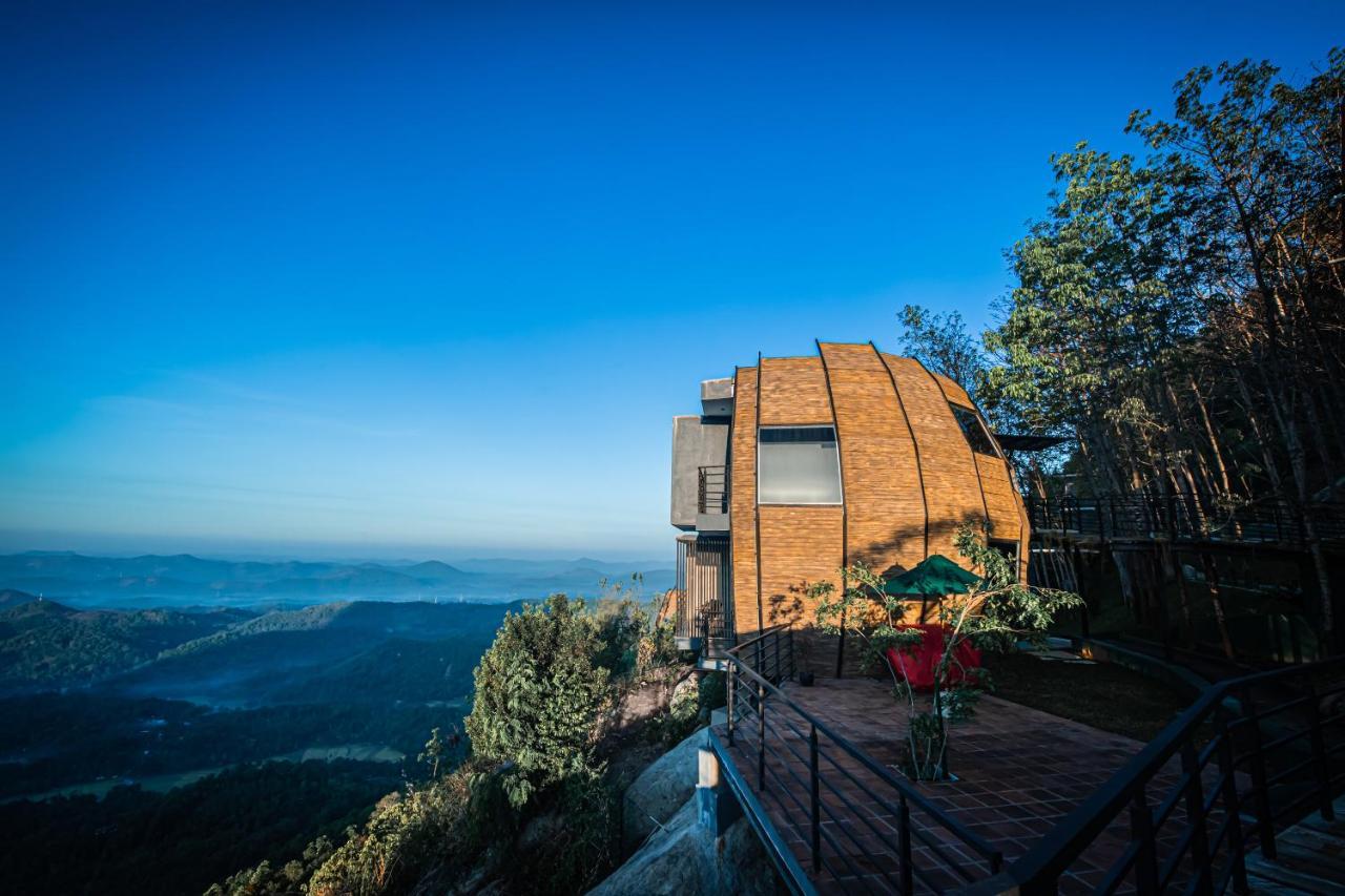 Greenacres Leisure Resort's distinctive dome-shaped building set against a deep blue sky on a mountain ridge, with layers of forested valleys visible in the distance below