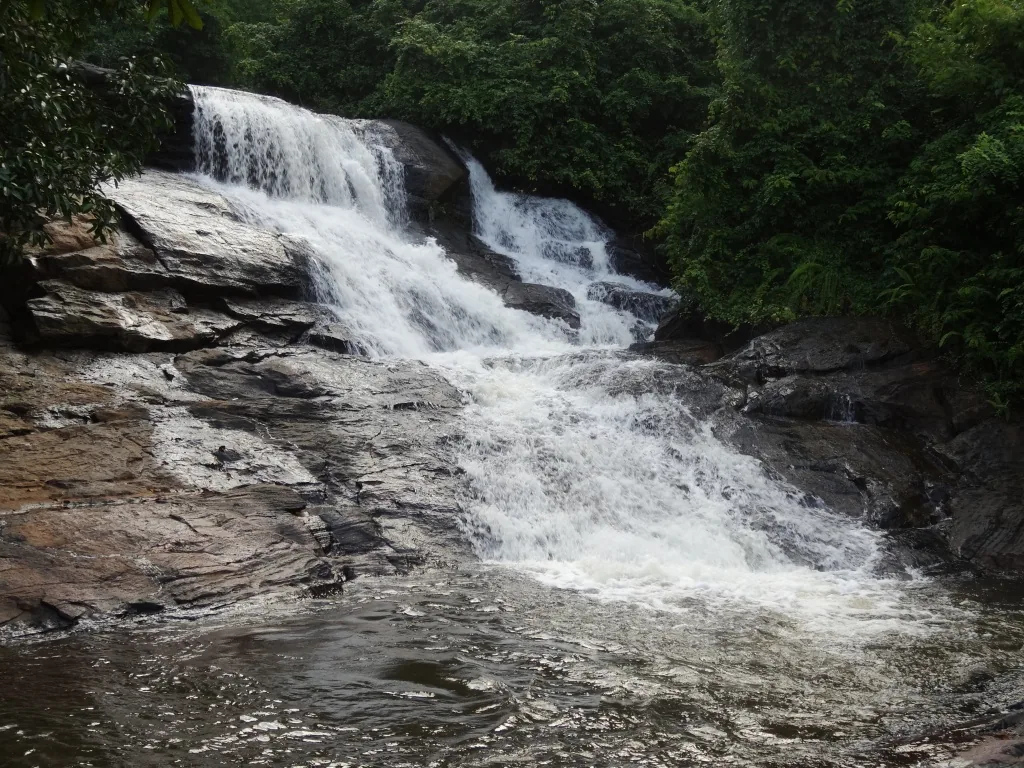 Thambadola Ella Falls cascading wide over flat granite rock steps in Kalutara District, Sri Lanka, surrounded by dense rainforest canopy
