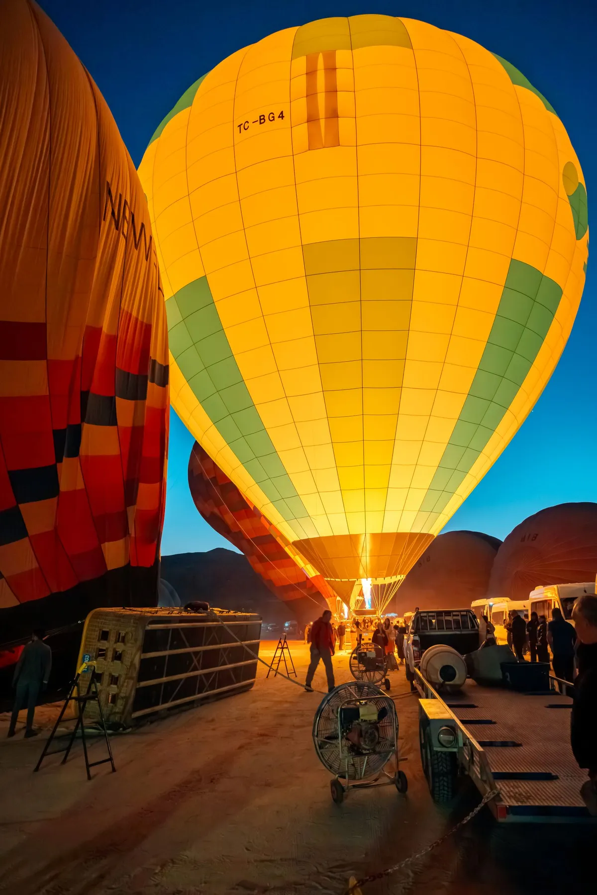 A hot air balloon being inflated and glowing at pre-dawn before a sunrise flight