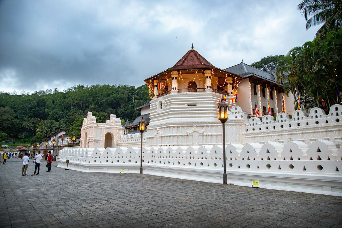 The Temple of the Tooth Relic (Sri Dalada Maligawa) in Kandy, Sri Lanka, with its distinctive burgundy roofline reflected in Kandy Lake