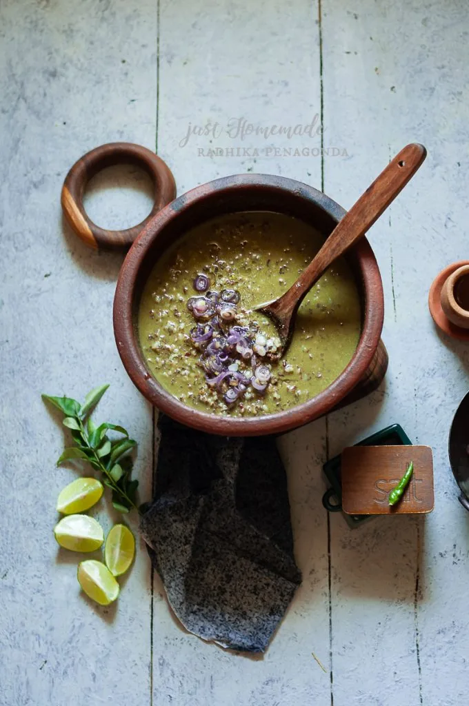 A glass of Kola Kanda herbal porridge served at a Sri Lankan breakfast counter showing the deep green colour and smooth consistency