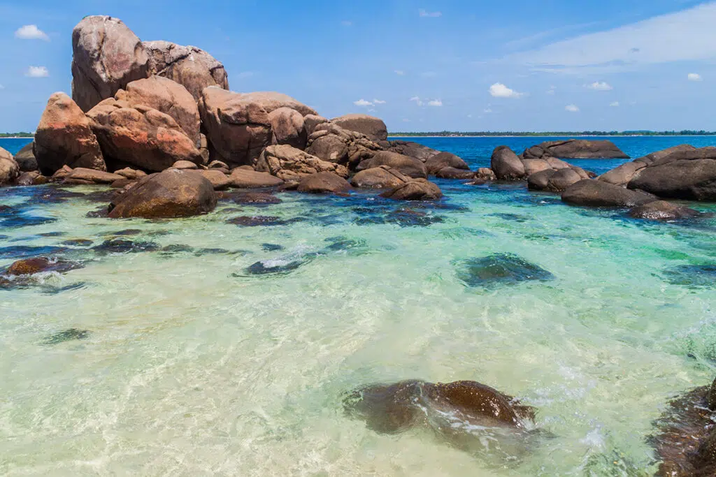Crystal-clear shallow water between large granite rock formations at Pigeon Island Marine National Park near Trincomalee, Sri Lanka