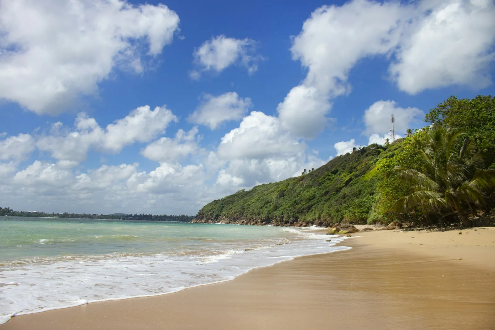 The sheltered crescent bay of Unawatuna beach with calm turquoise water and palm trees on Sri Lanka's south coast